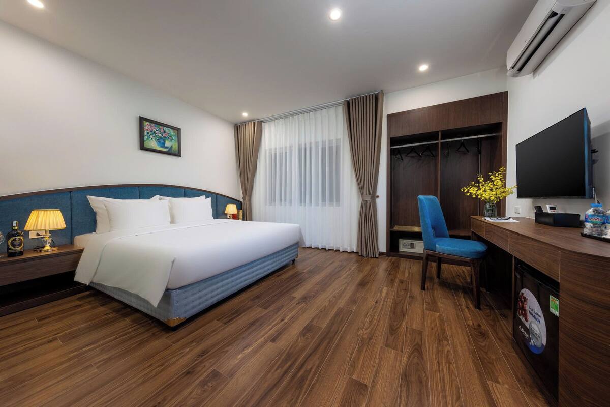 Ein Hotelzimmer mit einem Bett, einem Schreibtisch, einem Stuhl, einem Fernseher und einem Kleiderschrank.