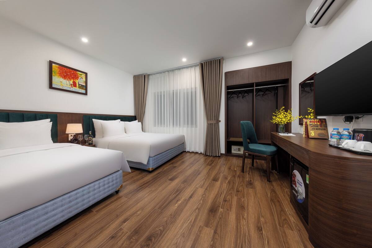 Ein Hotelzimmer mit zwei Betten, einem Schreibtisch, einem Stuhl, einem Fernseher und einem Kleiderschrank.