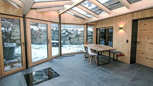 Een modern interieur met een houten vloer, een glazen deur naar buiten en een tafel met stoelen.