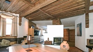 Een moderne woonkamer met een houten plafond, een bank, een salontafel en een open haard.
