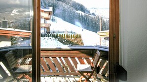 Een balkon met uitzicht op een besneeuwd berglandschap, inclusief een skilift en gebouwen.