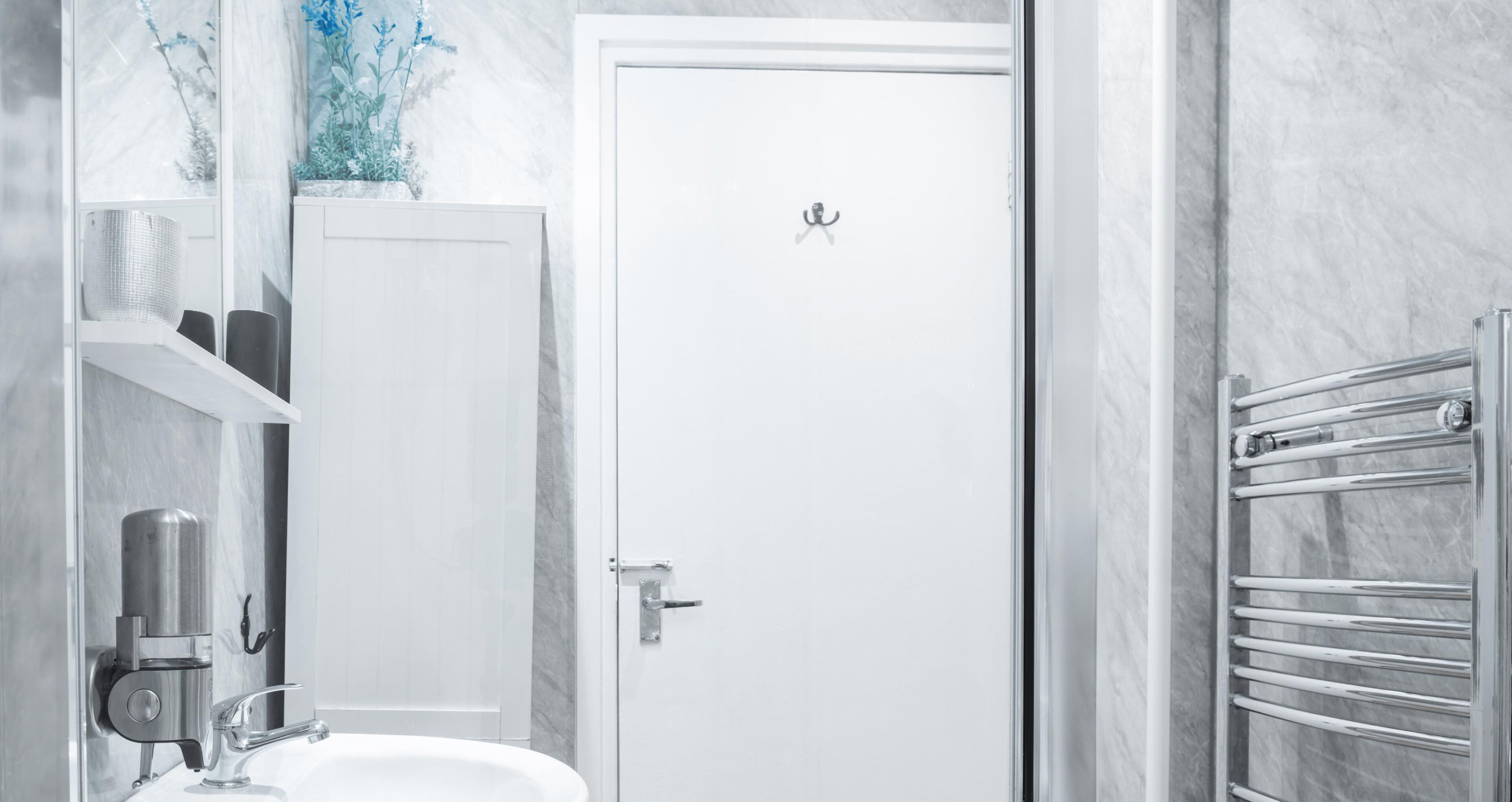 Een moderne badkamer met een witte deur, een ingebouwd wastafelmeubel en een handdoekhouder.
