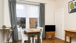 Ein gemütlicher Wohnraum mit Esstisch, Stühlen, einem Fernseher und einem kleinen Holztisch.