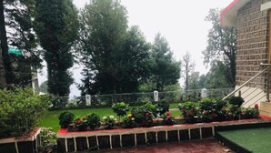 Um pátio com piso de tijolos, gramado verde e cerca de metal.