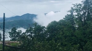 Paisagem montanhosa com floresta densa e um corpo d'água.