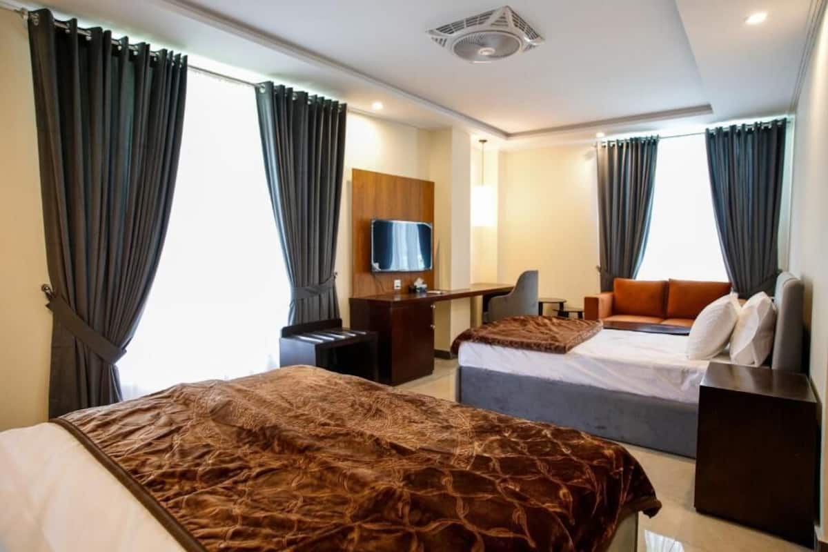 Una habitación de hotel con dos camas, un escritorio, un televisor y un sofá.