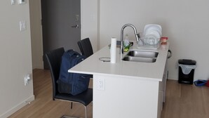 A compact kitchen with a sink, a chair, and a dining table.