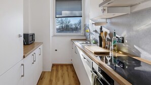 Cuina pràctica amb microones, rentapelats i taulell de fusta.