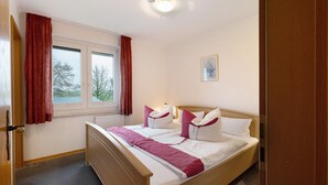 Une chambre à coucher avec un lit, une fenêtre, un radiateur et une porte.