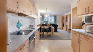 Une cuisine moderne avec des meubles en bois, une table à manger et un four à micro-ondes.