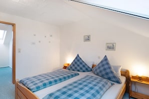 A single bed with checkered bedding, a bedside table with a lamp, and a small wall-mounted picture. - Apartment 'Annette' with Shared Terrace, Shared Garden and Wi-Fi (Nordstrand)