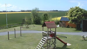 Une aire de jeux avec un toboggan, une balançoire et une structure d’escalade.