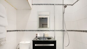 Un bagno con un WC bianco, un lavandino nero con uno specchio sopra e una zona doccia.
