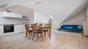 Una cocina moderna con armarios blancos, una mesa de comedor con sillas y un sofá azul en un espacio tipo loft.