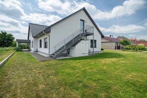 Une maison moderne à deux étages, dotée d’un escalier, d’un porche couvert et d’une pelouse bien entretenue.