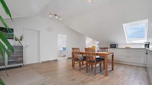 Una cocina moderna con una mesa de comedor, sillas, microondas y cafetera.