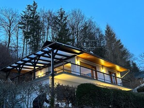 A modern two-story house with a balcony, surrounded by trees. - Apartment 'Grete' with Mountain View, Private Terrace and Wi-Fi (Diemelsee)
