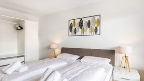 A hotel room with a large bed, two bedside tables, a wardrobe, and a wall art piece.