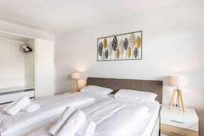A hotel room with a large bed, two bedside tables, a wardrobe, and a wall art piece. - Apartment 'Fritz' with Mountain View, Balcony and Wi-Fi (Diemelsee)
