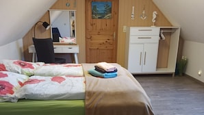 Une chambre à coucher comprenant un lit, un bureau, une chaise, une armoire et un tableau accroché au mur.