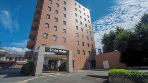 A tall brick building with a sign reading "Smile Hotel" at the entrance. - Smile Hotel Yonezawa (Yonezawa)