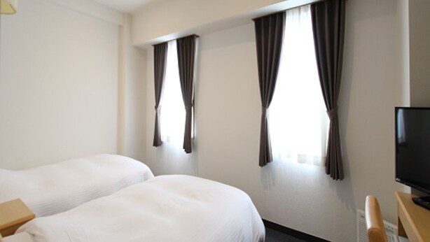 A hotel room with two single beds, a flat-screen TV, and a desk. - Smile Hotel Yonezawa (Yonezawa)