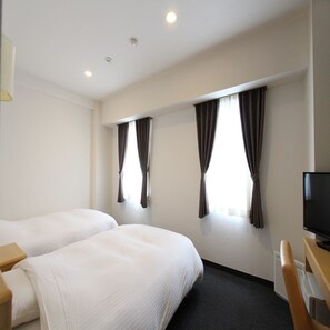 Une chambre d’hôtel avec deux lits simples, un téléviseur à écran plat et un bureau.