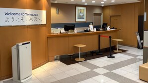 A reception area with a sign reading "Welcome to Yonezawa," a reception desk, a refrigerator, and a clock on the wall. - Smile Hotel Yonezawa (Yonezawa)