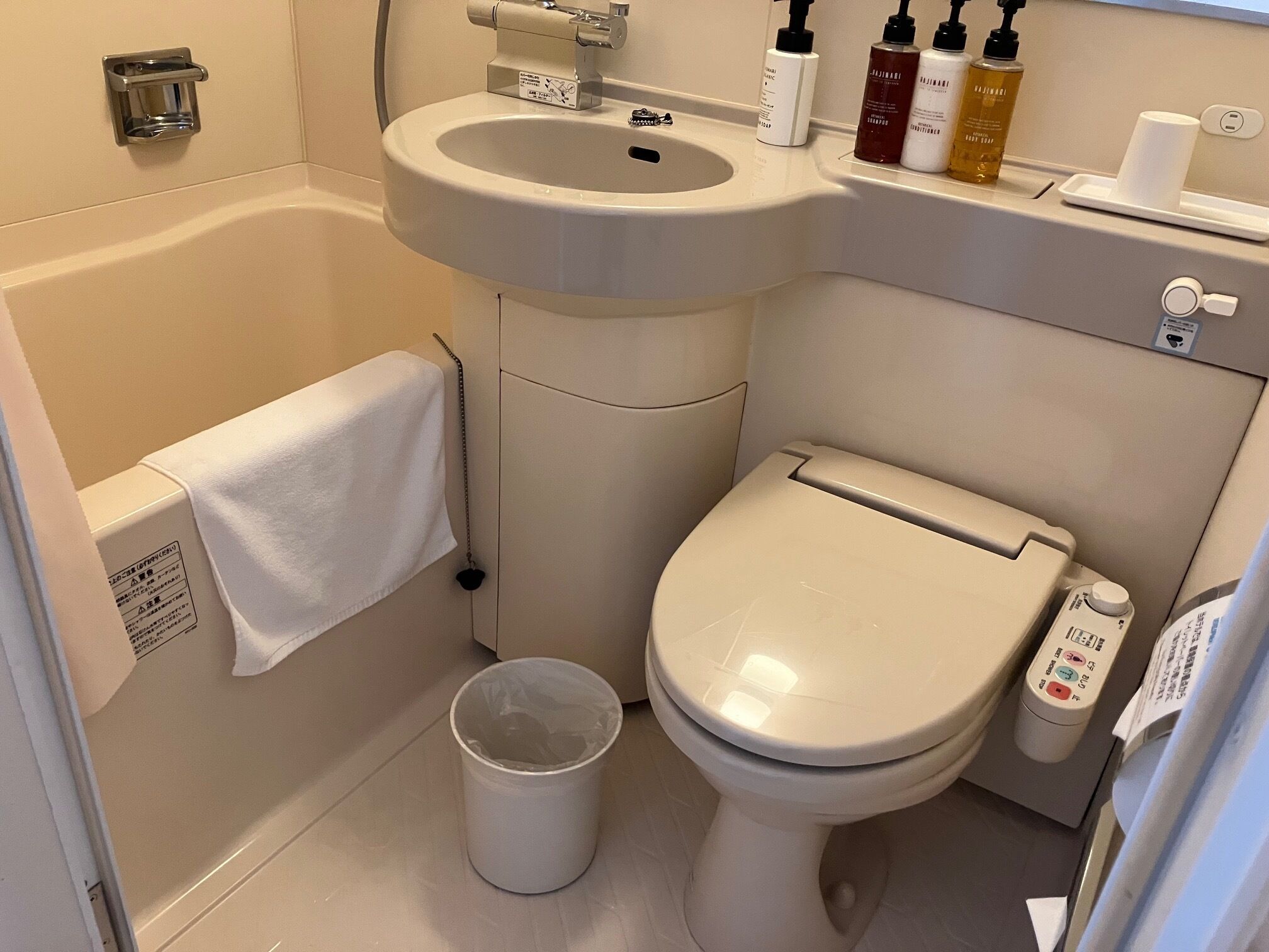 Une salle de bain équipée d’un lavabo, de toilettes et d’une poubelle.