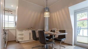 Una cocina moderna con zona de comedor, que presenta una mesa de madera, sillas negras y una lámpara colgante.