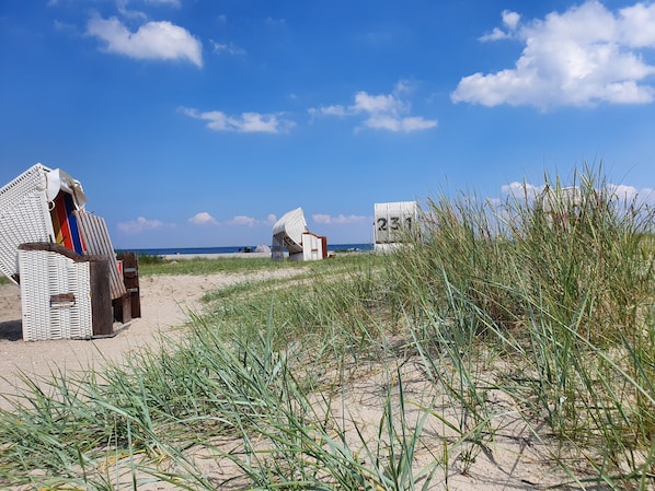 Beach huts with a sandy foreground and a clear blue sky.