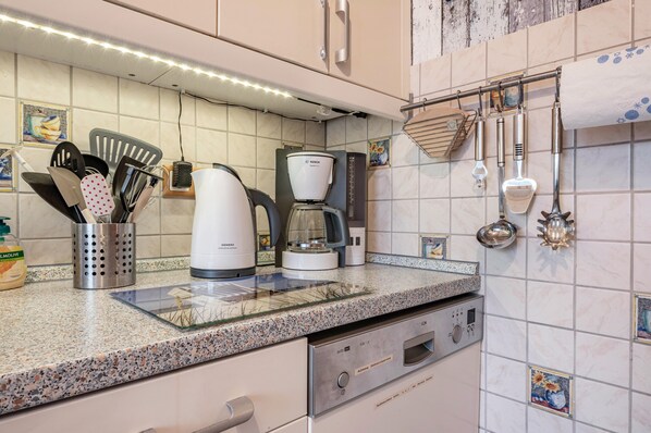 A kitchen with a coffee maker, utensils, and a dishwasher. - Holiday Home 'Haus Strandliebe' with Private Terrace, Private Garden and Wi-Fi (Wangerland)