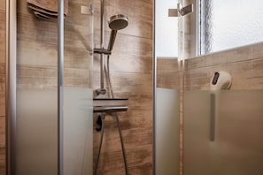 A modern shower with a handheld showerhead, a handheld shower attachment, and a soap dispenser.