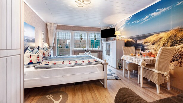 Ein Schlafzimmer mit einem Bett, einem Schreibtisch, einem Stuhl, einem Fernseher und einem großen Fenster.