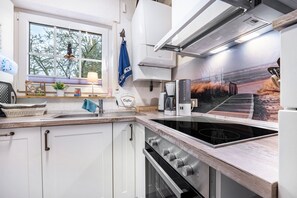 Una cucina con piano cottura, lavello e finestra vista alberi.