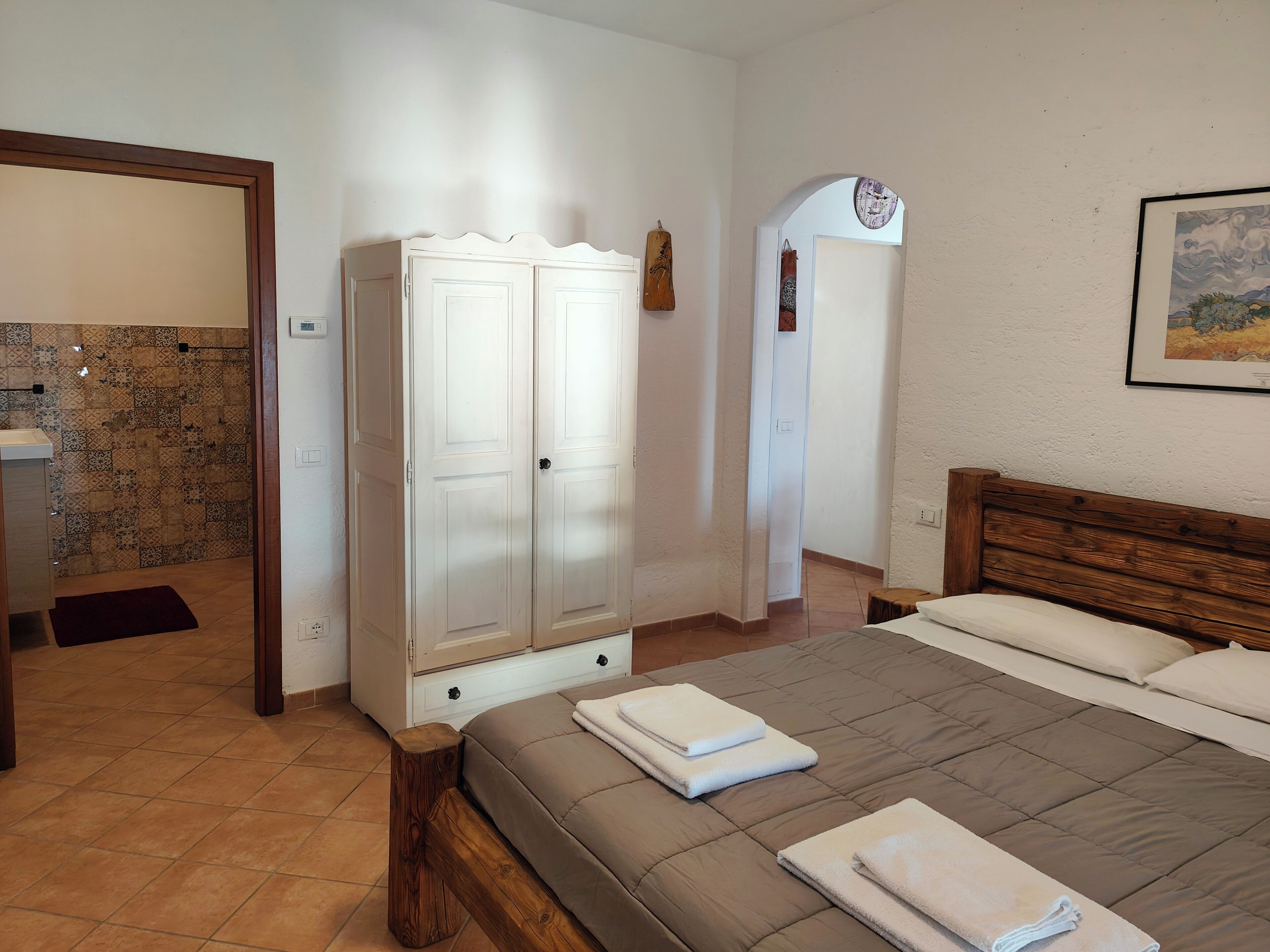 Un dormitorio con cama, armario, baño y un pasillo.
