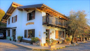 A two-story building with a balcony, potted plants, and a small dog house. - Agriturismo Scuderia Castello (Toscolano Maderno)