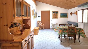 A dining area with a wooden table, chairs, and a cabinet with glass doors. - Agriturismo Scuderia Castello (Toscolano Maderno)