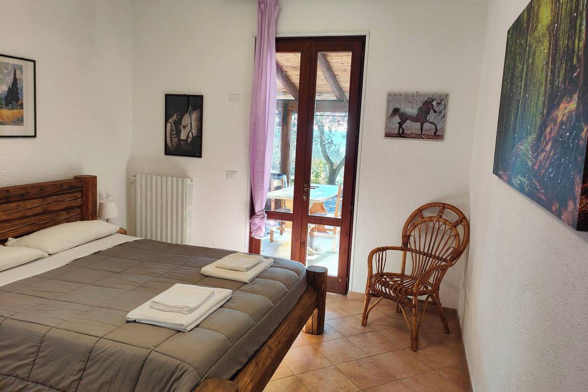 A bedroom with a bed, a chair, and a door leading to an outdoor area.