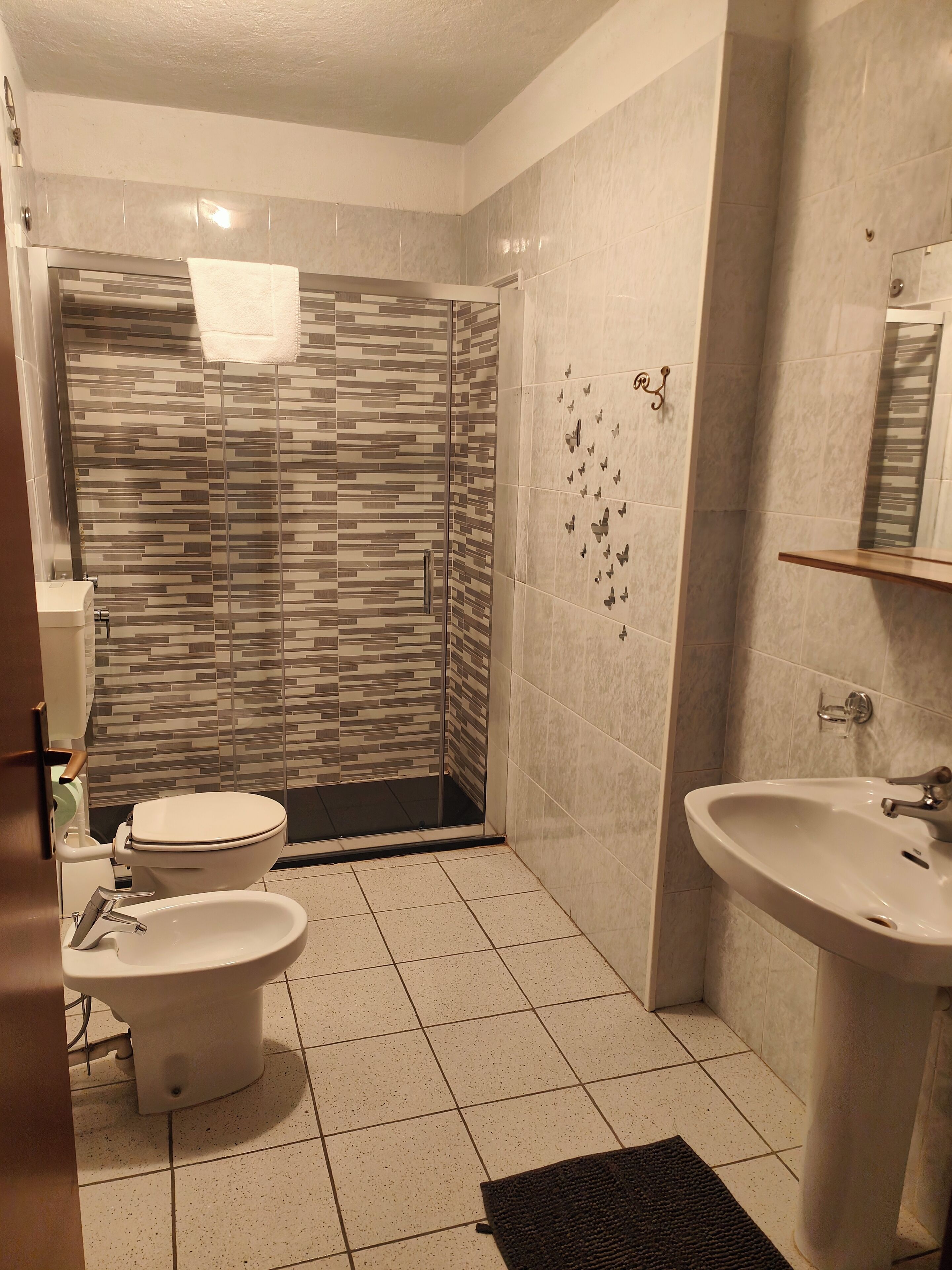 A bathroom with a toilet, bidet, sink, and shower area.