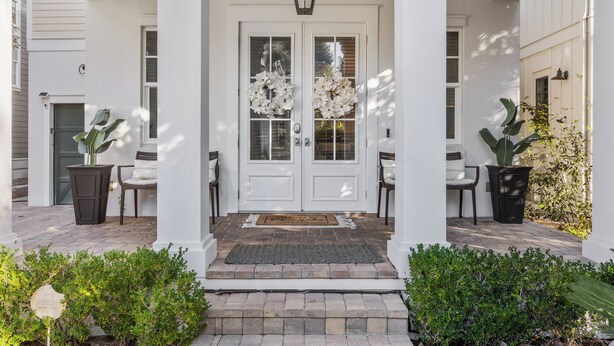 A white building with a double door, two potted plants, and a brick pathway leading to the entrance. - Seagrove Gardens | Mins to the Beach, Santa Rosa Retreat w/ A+ Design (Santa Rosa Beach)