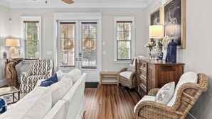 A living room with a ceiling fan, a sofa, a chair, a small table, and a cabinet. - Seagrove Gardens | Mins to the Beach, Santa Rosa Retreat w/ A+ Design (Santa Rosa Beach)