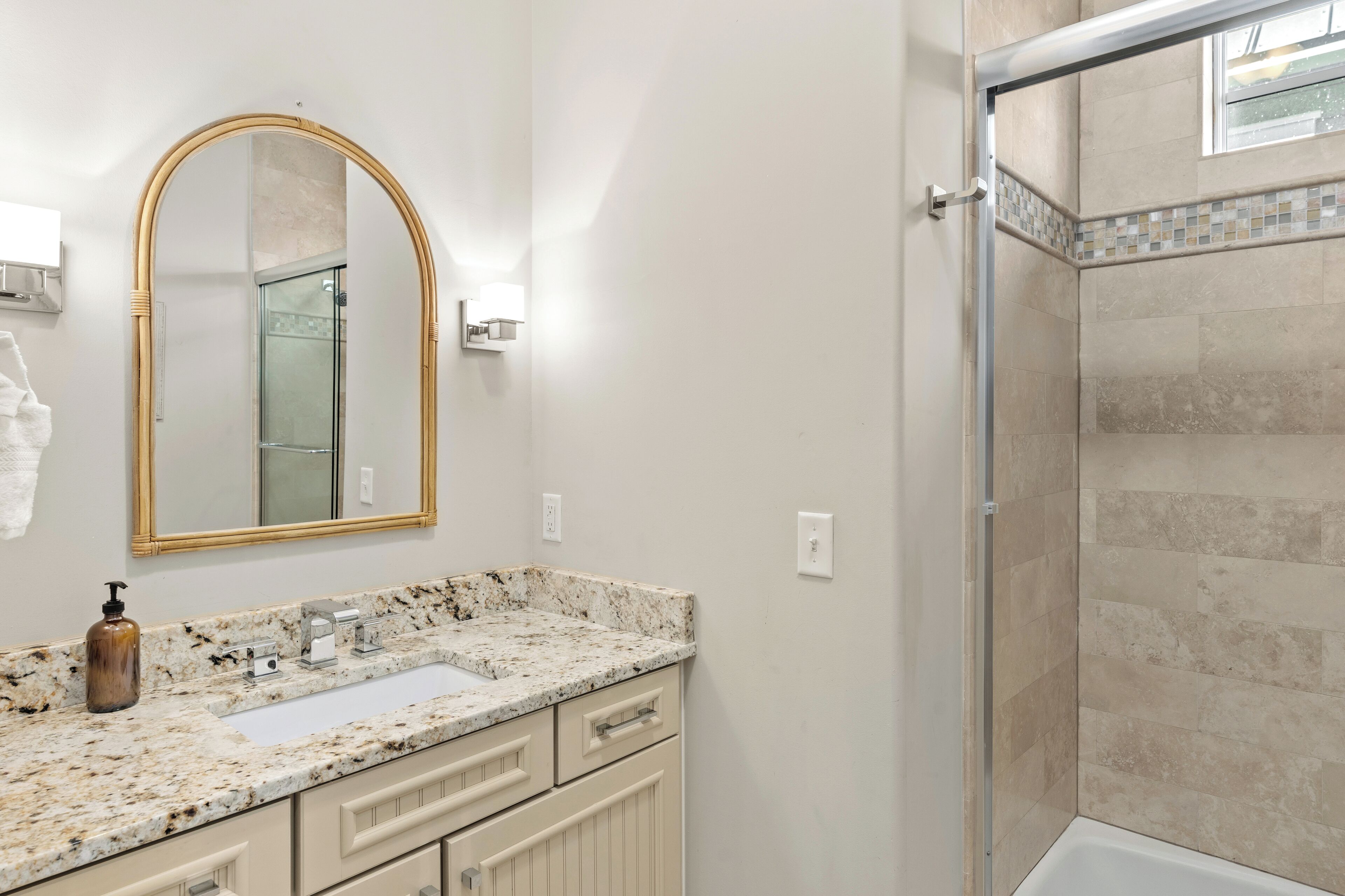 A bathroom with a marble sink, a large mirror, and a shower area.