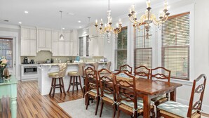 A spacious kitchen with white cabinetry, a wooden dining table, and a chandelier. - Seagrove Gardens | Mins to the Beach, Santa Rosa Retreat w/ A+ Design (Santa Rosa Beach)