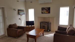 A living room with a fireplace, two sofas, a coffee table, and a television. - Hillocks Homestead Overlooking the Bush (Marion Bay)
