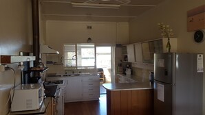 A kitchen with a stove, sink, refrigerator, and wooden cabinets. - Hillocks Homestead Overlooking the Bush (Marion Bay)