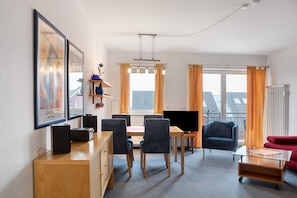 Una sala de estar moderna con comedor, televisor y sofá.