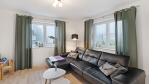 A modern living room with a leather sofa, a small table, a lamp, and a view of the outside. - Apartment 'Hildas Plätzchen' with Private Terrace and Wi-Fi (Oberkirch)