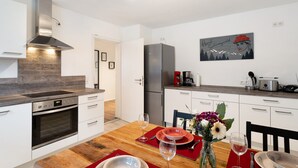 A modern kitchen with white cabinets, a stainless steel range hood, a built-in oven, and a refrigerator. - Apartment 'Hildas Plätzchen' with Private Terrace and Wi-Fi (Oberkirch)