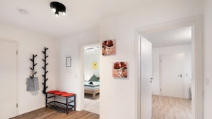 A hallway with a coat rack, a bench with red cushions, and artwork on the walls. - Apartment 'Hildas Plätzchen' with Private Terrace and Wi-Fi (Oberkirch)